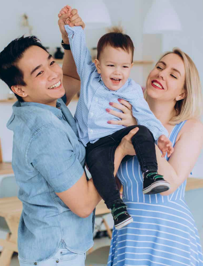  This photo shows a happy family, potentially at a family dentistry practice, with parents holding their young child who is laughing joyfully.